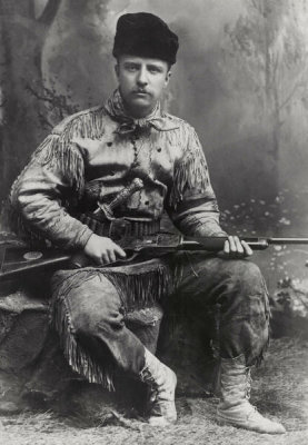 George Grantham Bain - Theodore Roosevelt, seated, in deer skin hunting suit, holding rifle, 1885